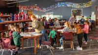 Watford City elementary students work in the library with Burgum Scholar Olivia Dwyer