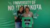 Two ladies smile for the camera at the tailgating tent to celebrate milestone grads 