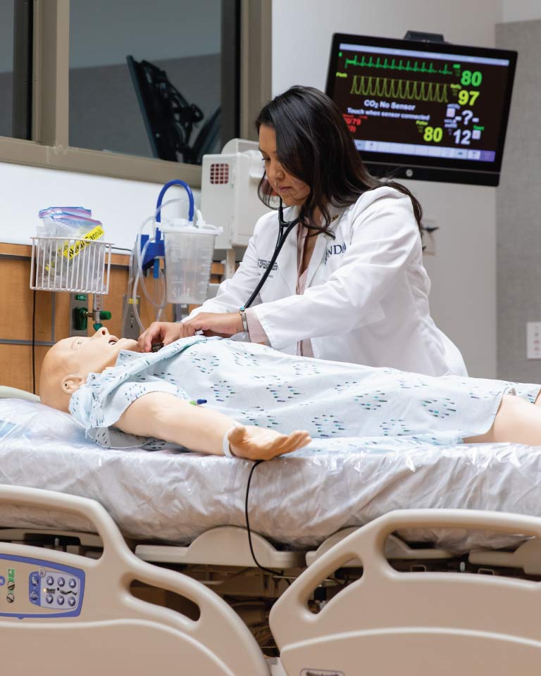 Female medical student practicing assessing a patient.