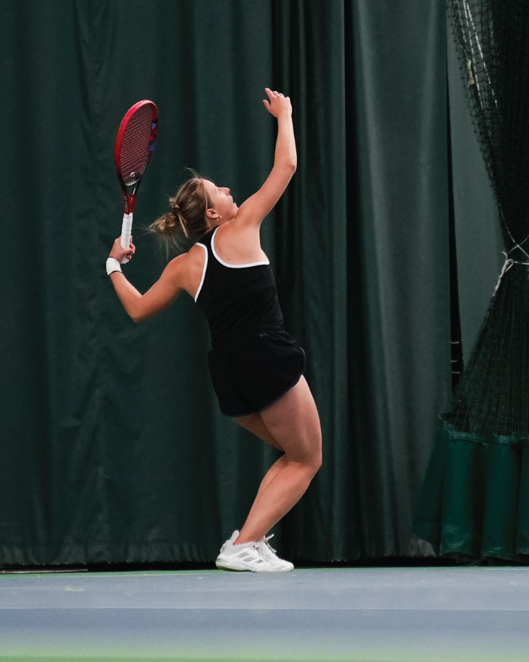 Woman serving tennis ball