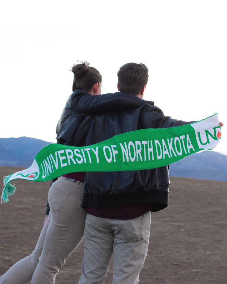 Man and woman holding UND scarf