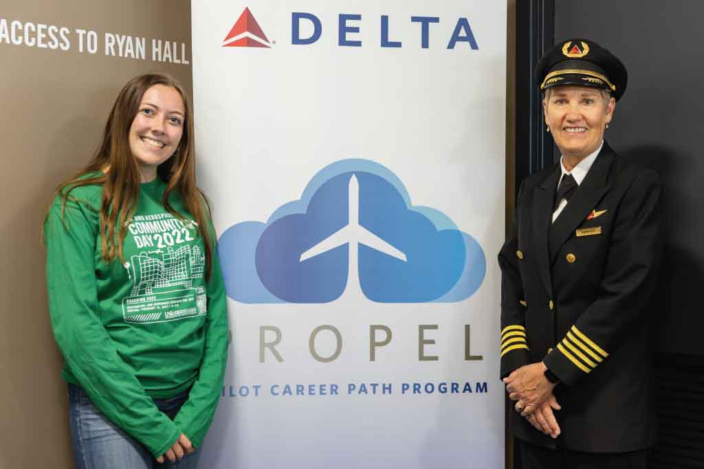 Sophia Jensen and Karen Ruth pose beside a Delta Airlines sign