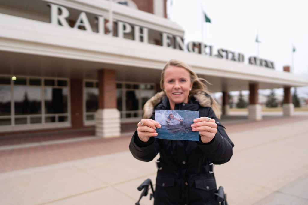 Brittany Dvorack holding a photo of her swimming with the dolphins 