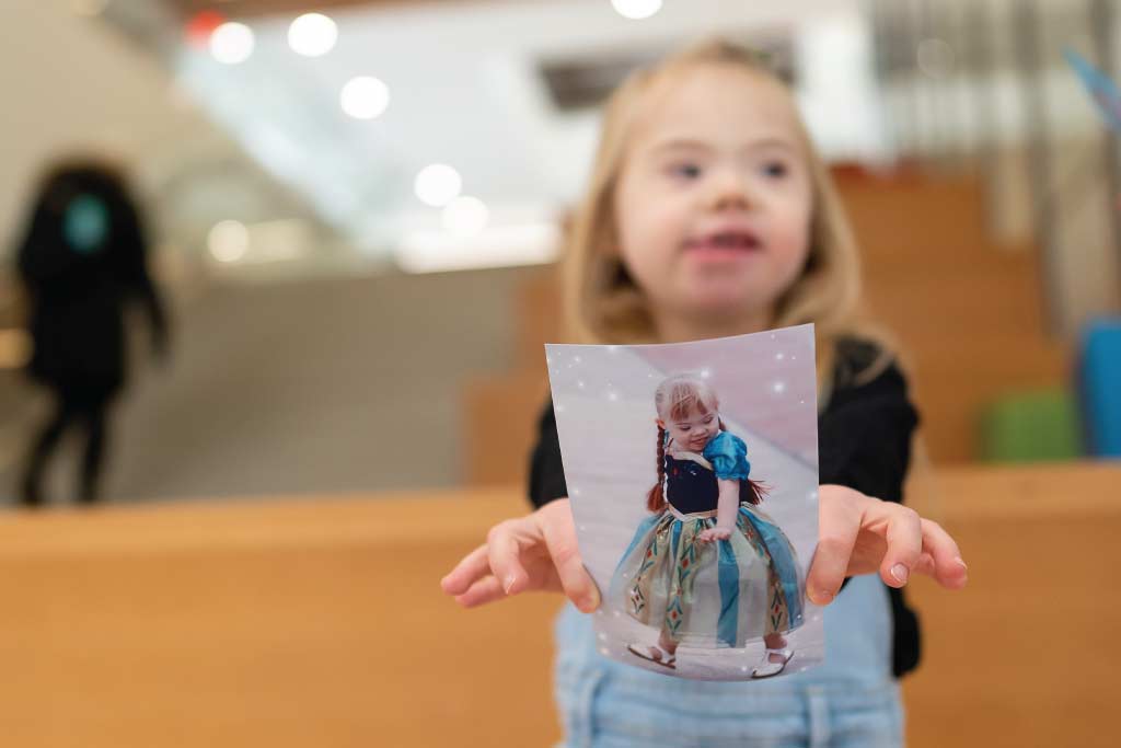 Clara holding a photo of her dressed as a princess