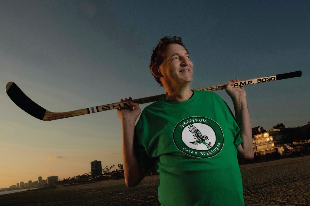 Bill holds a hockey stick while wearing a green shirt