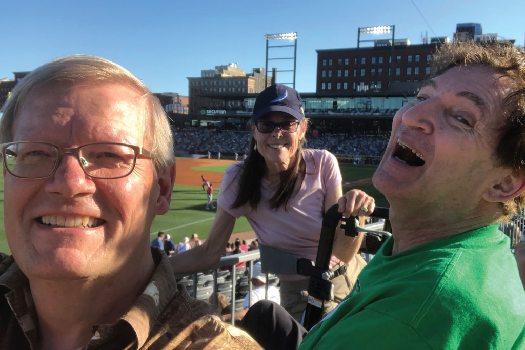 three people laugh at a baseball game
