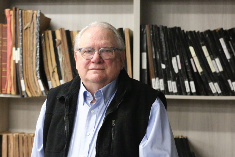 Fred Bartz sitting in front of shelves in a library