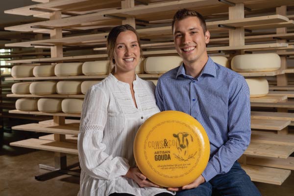 Maartje and Casey Murphy holding a wheel of gouda cheese