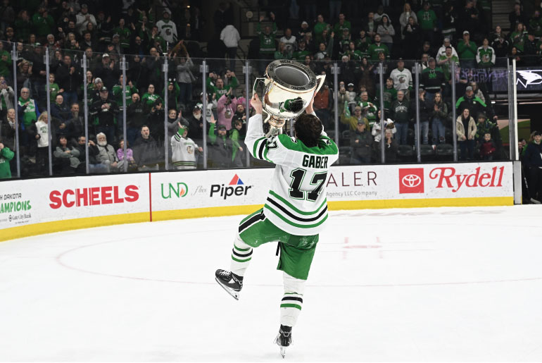 Riese Gaber with large trophy on hockey ice