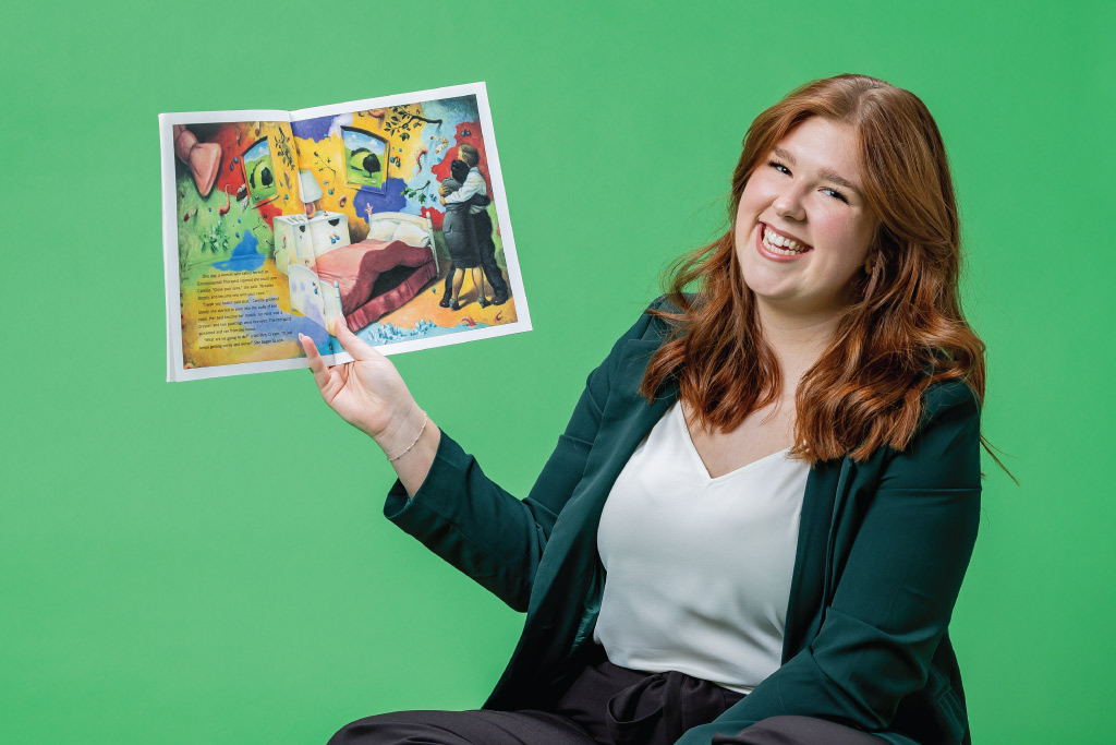 emma rudolph holding children's book and laughing on green background