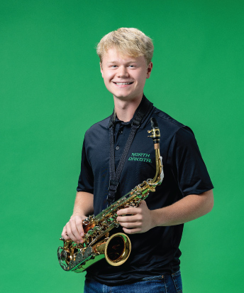 person on green backdrop holding saxophone